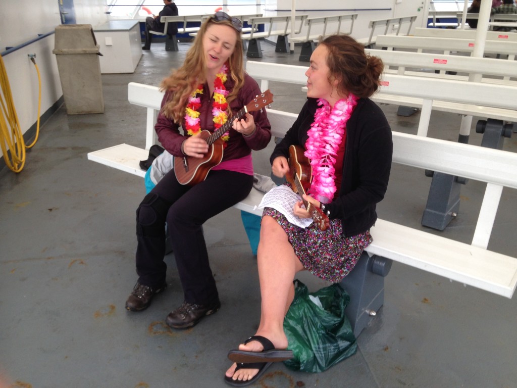 Cora and Roseanna playing ukulele on ferry over. Photo by Jake Jones.