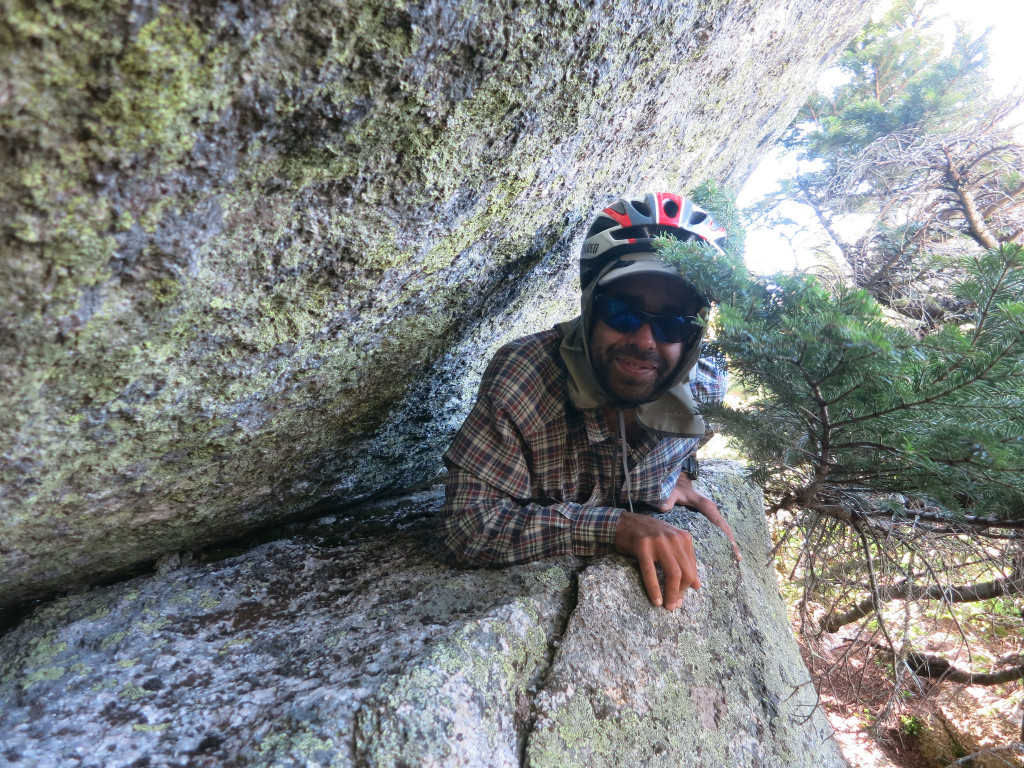 Alberto crawling underneath the boulder blocking the route.