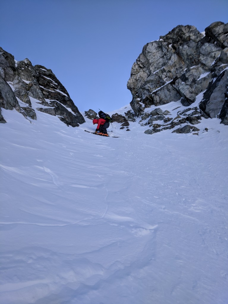 Olek putting on his skis at the rocky entrance to the Eureka NW couloir.