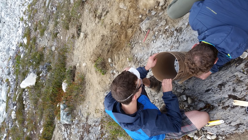 Lukas and Luc marking the sonotubes with a sharpie how the sonotubes needed to but cut so that they would sit flush on the bedrock. 