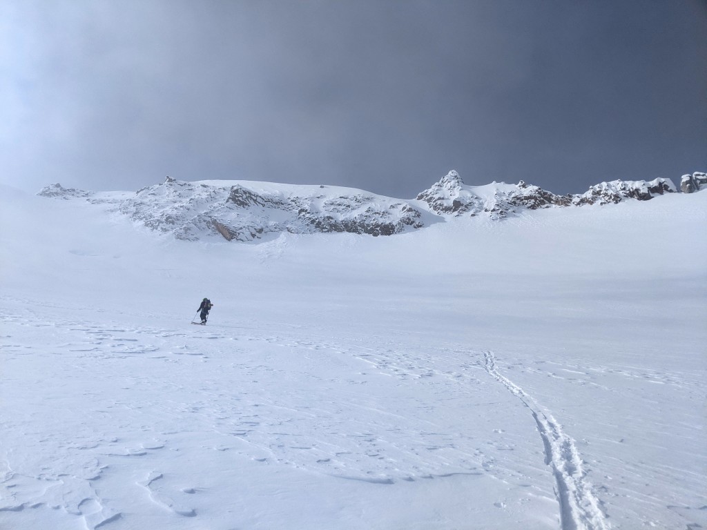 Skinning up the summit tower as the clouds roll in briefly.