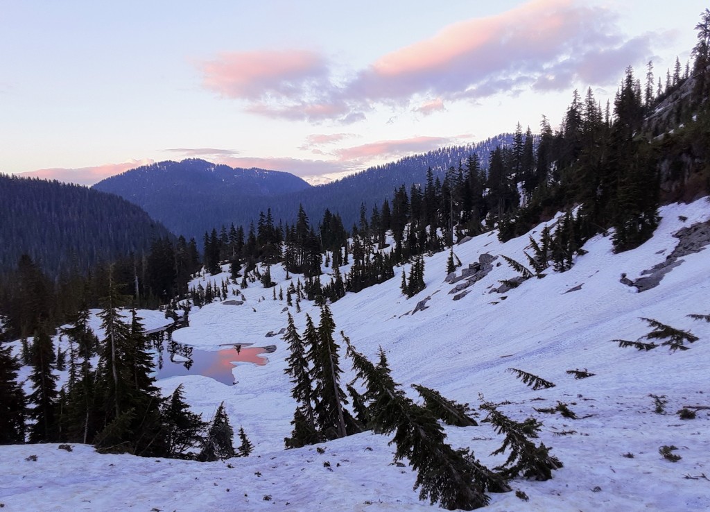 Half-frozen tarn reflecting the sunset