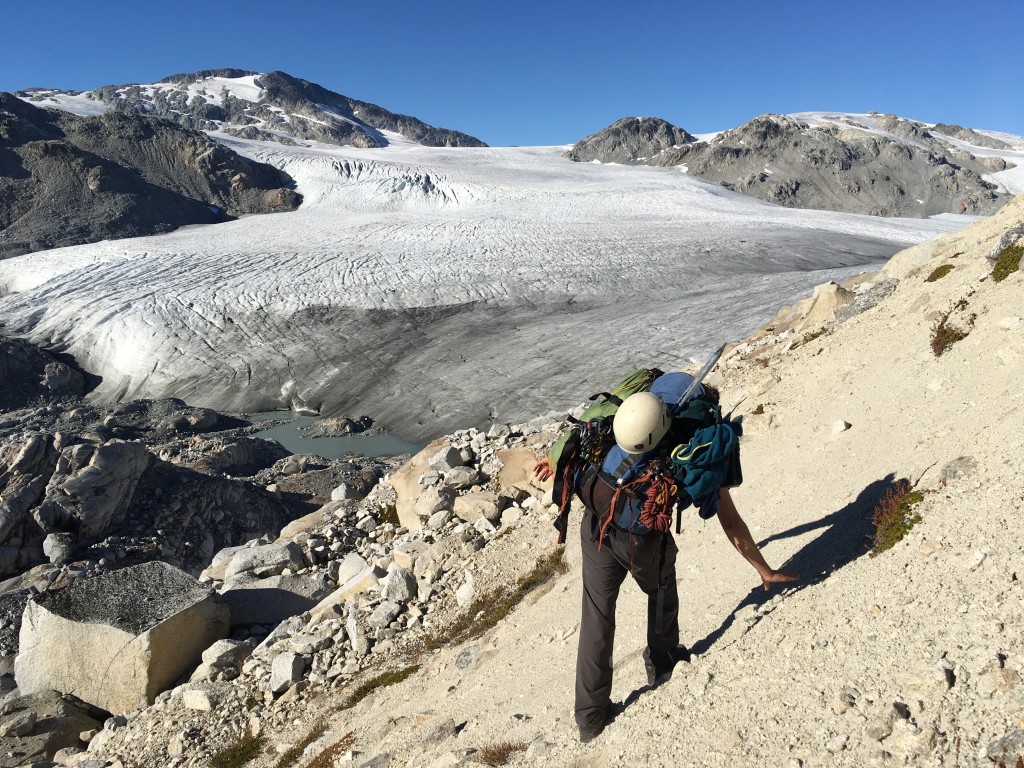 Thomas sidling down a loose moraine towards Exodus Glacier, with Exodus Peak in the top left (John Commissaris)