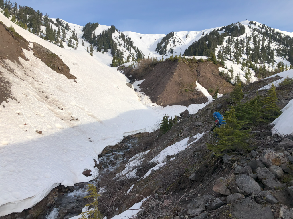 Hiking down some loose rubble to cross a tributary of Ring Creek and get back onto snow.