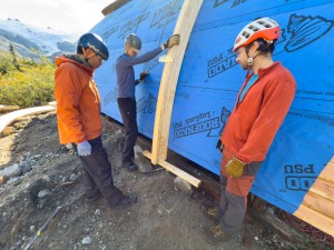 Classic construction, one guy holding the work while two more stare at it.