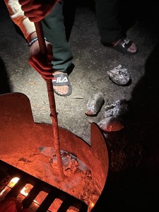 Alex getting the baked potatoes out of the fire.